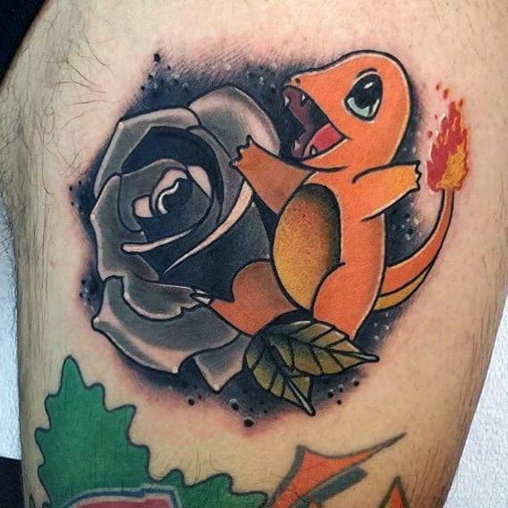 Charmander tattoo beside a black and gray rose with fiery tail and bold shading, blending floral and character art on upper thigh.