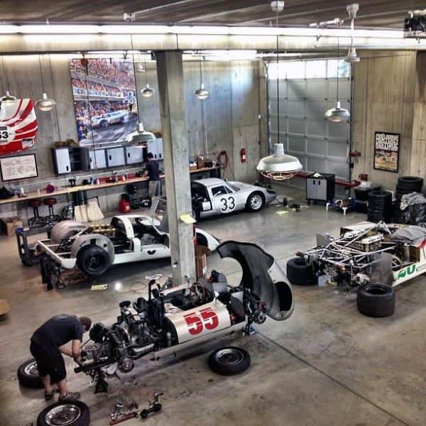 A bustling garage with race cars being worked on, tools and equipment scattered across the floor