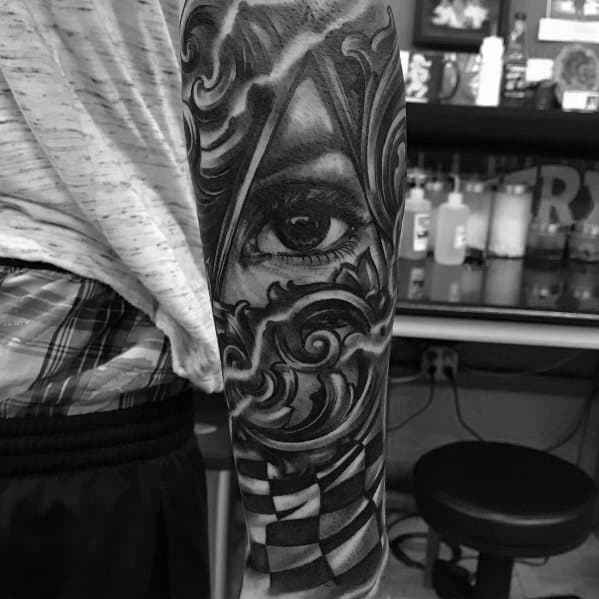Intricate sleeve tattoo featuring a realistic eye, ornamental designs, and a checkered flag, blending racing symbolism with artistic detail.