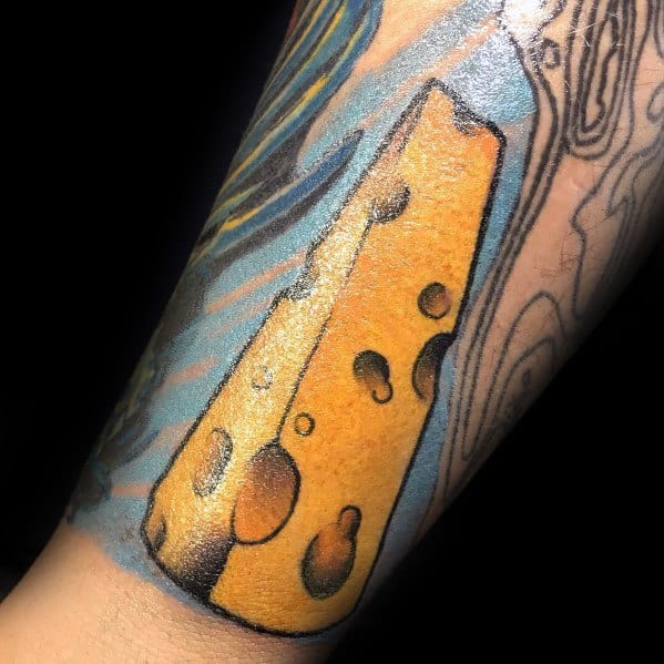 Vibrant tattoo of a large wedge of Swiss cheese with bold black outlines and rich yellow shading, set against a blue abstract background.
