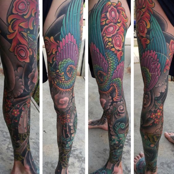Full leg sleeve tattoo featuring a vibrant phoenix with teal and purple feathers, surrounded by cherry blossoms and intricate Japanese patterns
