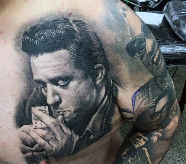 Highly detailed Elvis Presley tattoo on the upper back, showing him lighting a cigarette with a contemplative look.