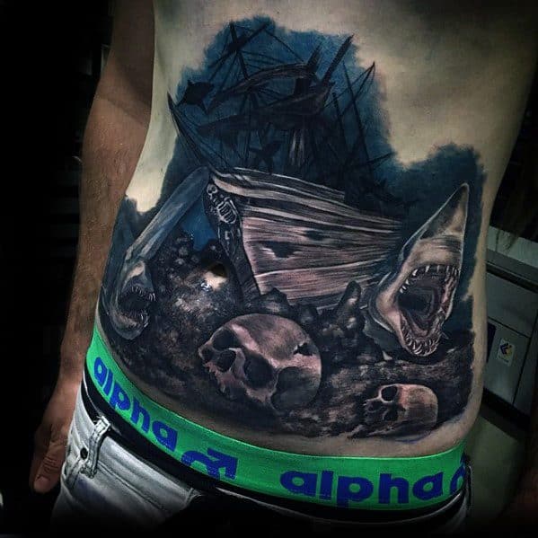 Dark shipwreck tattoo on the torso featuring a sunken ship, skulls, bones, and a menacing shark emerging from the debris.