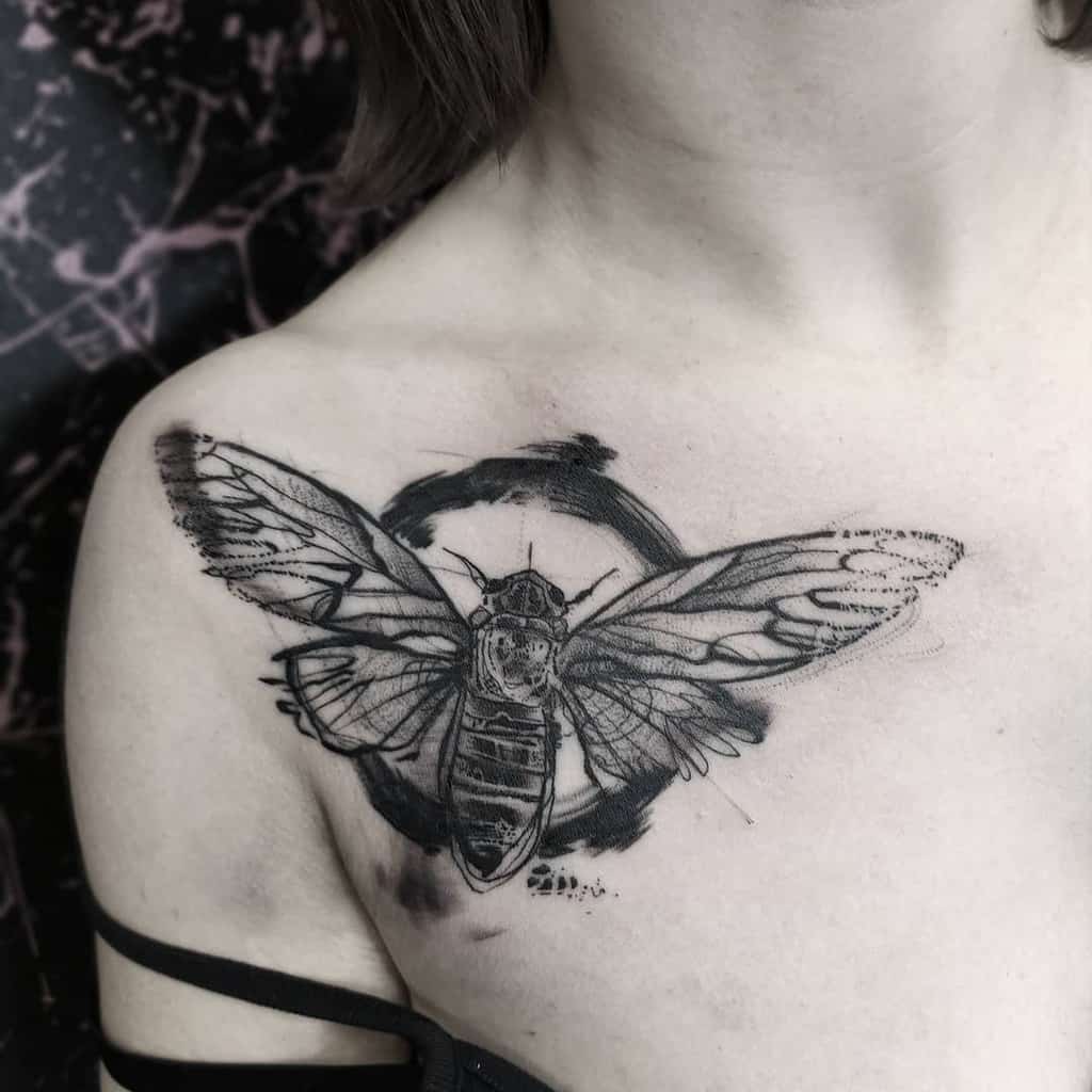 A detailed cicada tattoo on a person's shoulder with abstract black ink accents