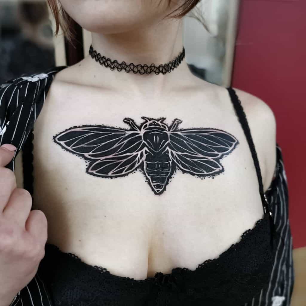 Woman with a large black cicada tattoo on her chest