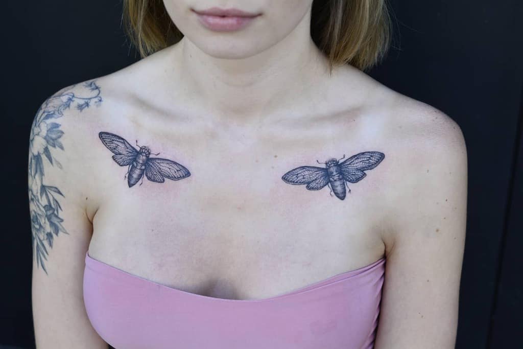 Woman with cicada tattoos on shoulders and a floral tattoo on arm