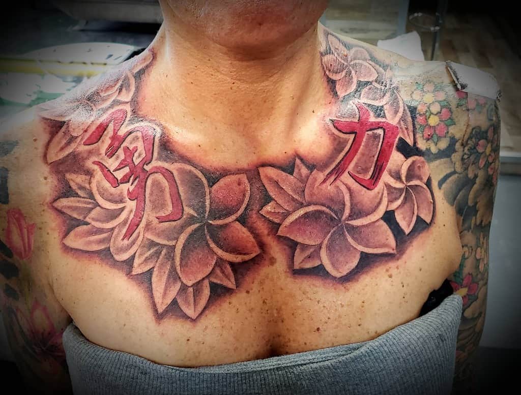 Chest tattoos of plumeria flowers and red Kanji characters