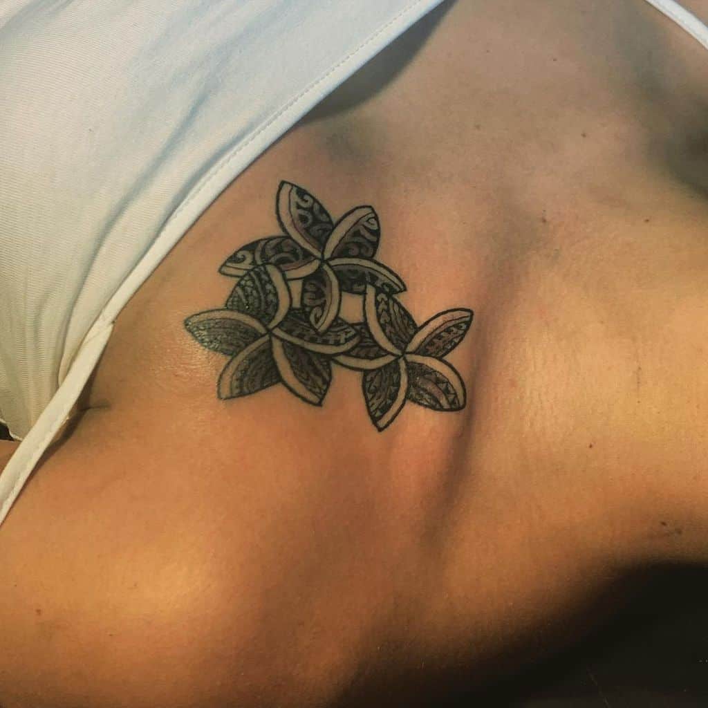 This minimalist chest tattoo features intricately detailed Plumeria flowers with Polynesian-inspired patterns, creating a harmonious blend of cultural artistry and natural elegance