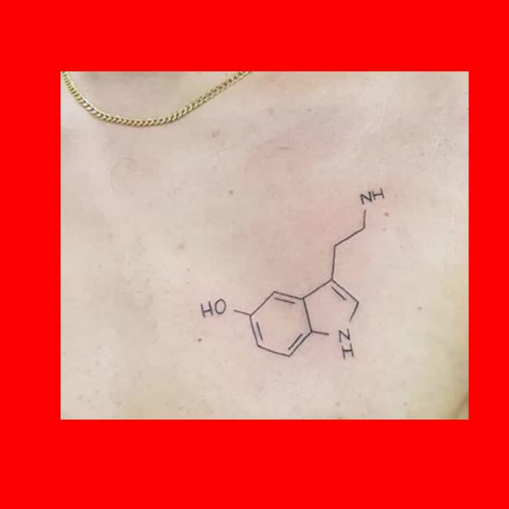A delicate tattoo of a serotonin molecule graces the person's chest, symbolizing balance and happiness