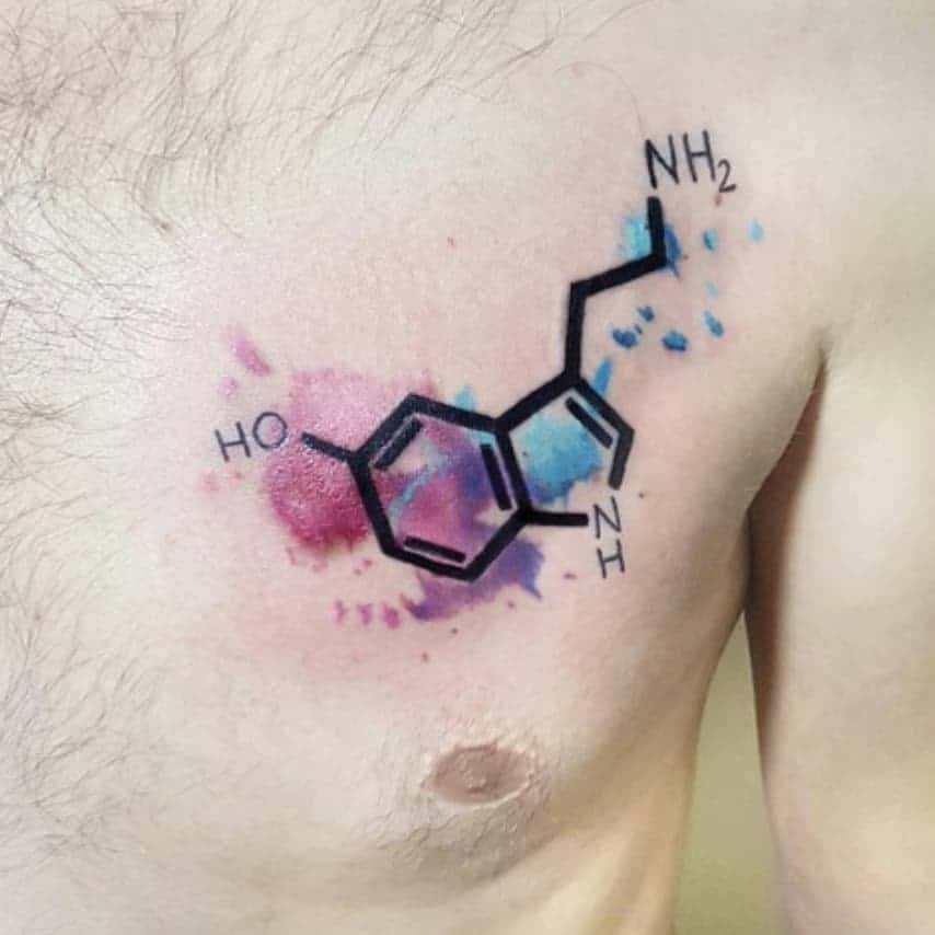 A tattoo of the serotonin molecule graces the chest, set against a vibrant watercolor background