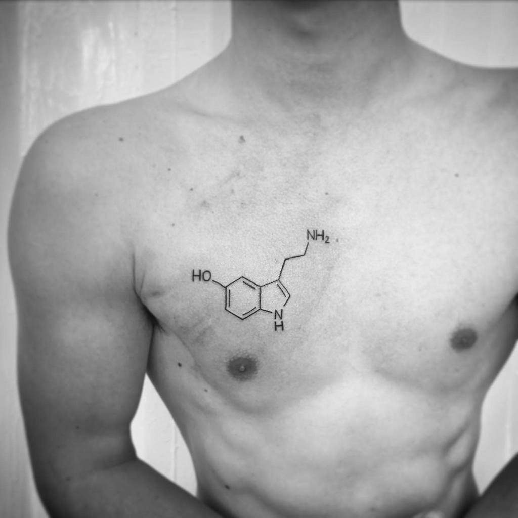 A person proudly displays a detailed serotonin molecule tattoo across their chest, symbolizing their connection to happiness and well-being