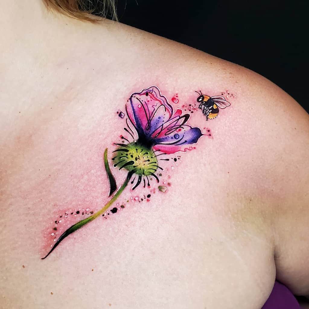 A vibrant flower tattoo adorns the shoulder, with a bee gracefully hovering near a delicate thistle