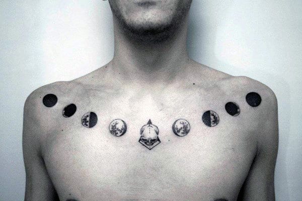 Man displaying moon phase tattoos across his chest with a central geometric design below his clavicle