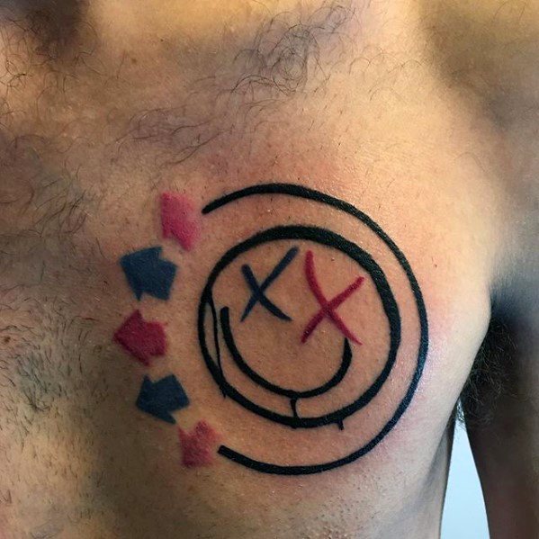 Tattoo of the Blink-182 smiley face logo with bold black outlines, featuring red and blue arrows, placed on the chest.