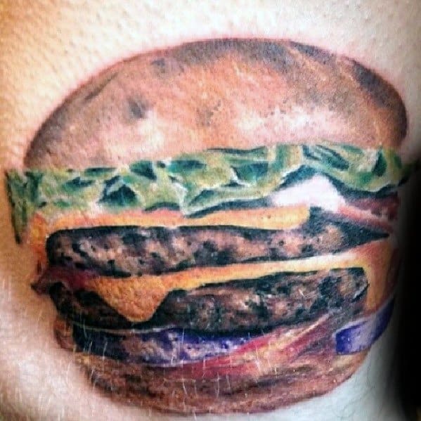 Realistic tattoo of a cheeseburger with lettuce, melty cheese, and beef patties