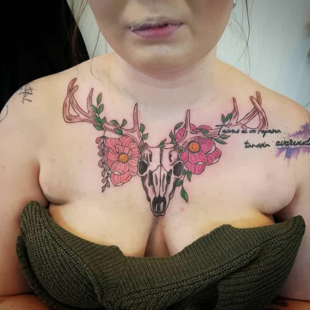 Chest tattoo of a deer skull, its regal antlers adorned with delicate flowers, elegantly inked across their chest