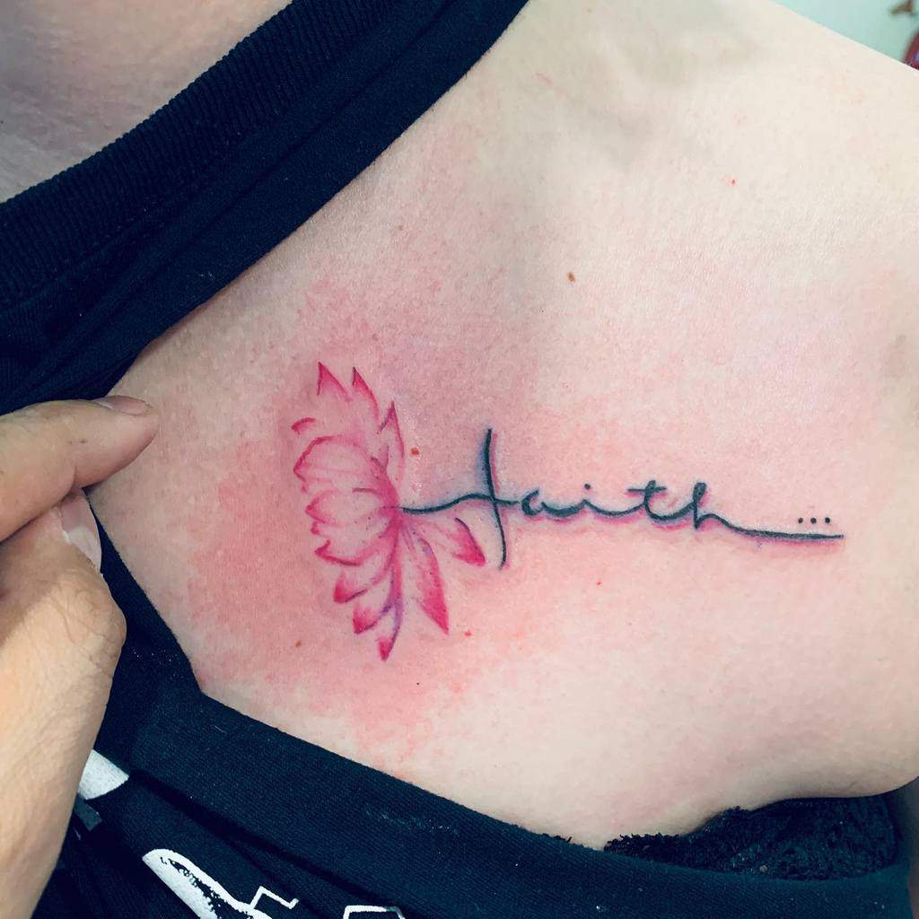 A floral tattoo elegantly adorns a person's shoulder, intertwining the word "faith" with the delicate symbolism of a cross