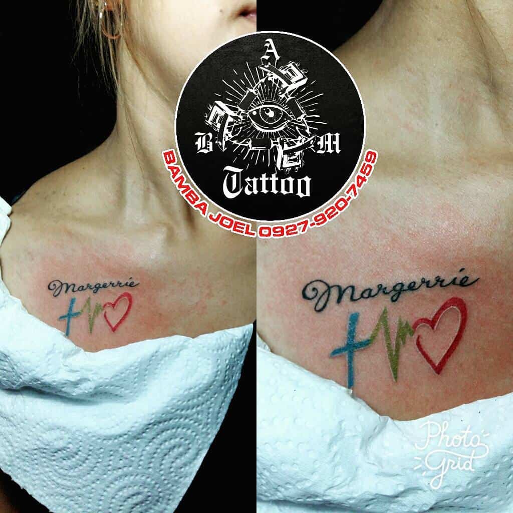 Chest tattoo with the name 'Margerrie' in cursive above symbols of faith, hope, and love: a blue cross, green heartbeat line, and red heart, representing deep personal values