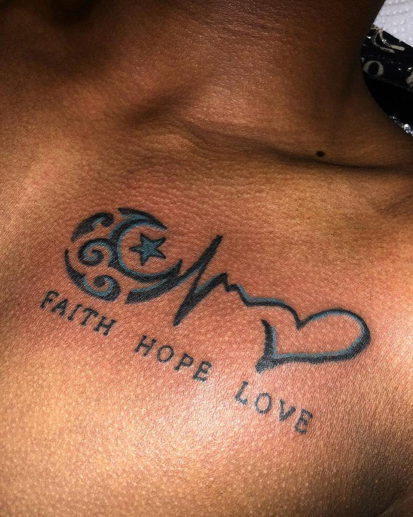 A chest tattoo on dark skin elegantly combines symbols with the heartfelt words "Faith, Hope, Love," capturing a profound message through art