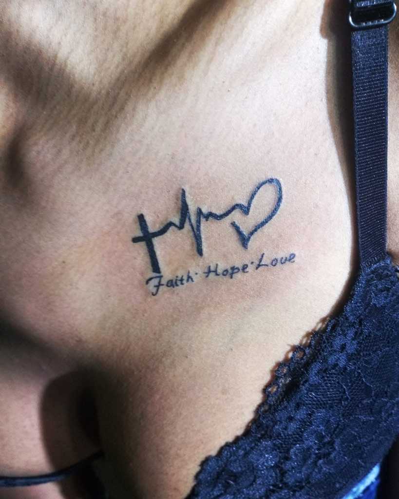 Tattoo on the upper chest featuring a cross, heartbeat line, and heart, beautifully intertwined with the words "Faith Hope Love"