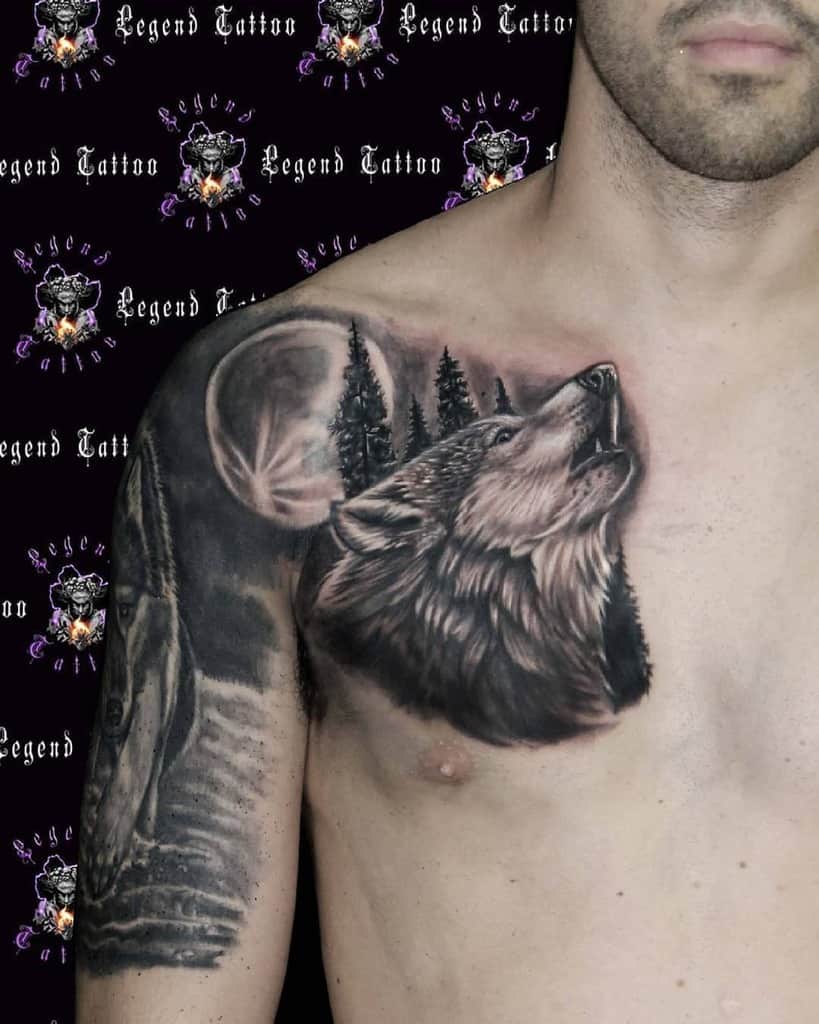 A striking wolf and forest tattoo graces a man's chest and shoulder