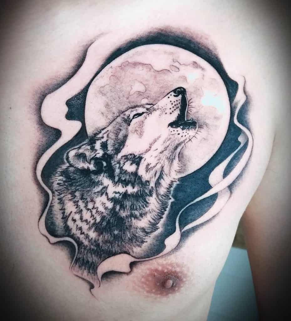 A stunning tattoo of a wolf howling at the moon is beautifully etched on a person's chest, surrounded by intricate, smoke-like patterns