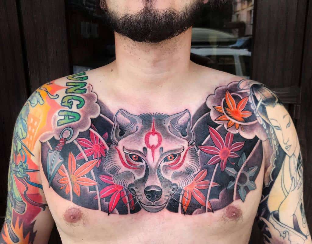 Bold chest tattoo depicting a Japanese-style wolf with intense red markings, surrounded by vibrant red and orange maple leaves, blending into traditional Japanese tattoo motifs across the chest and shoulders