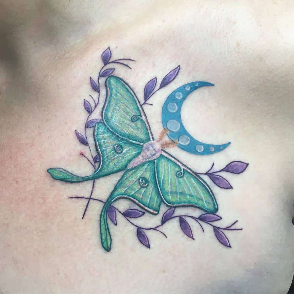 A colorful Luna Moth tattoo with purple leaves and a crescent moon, featuring intricate green and blue shades
