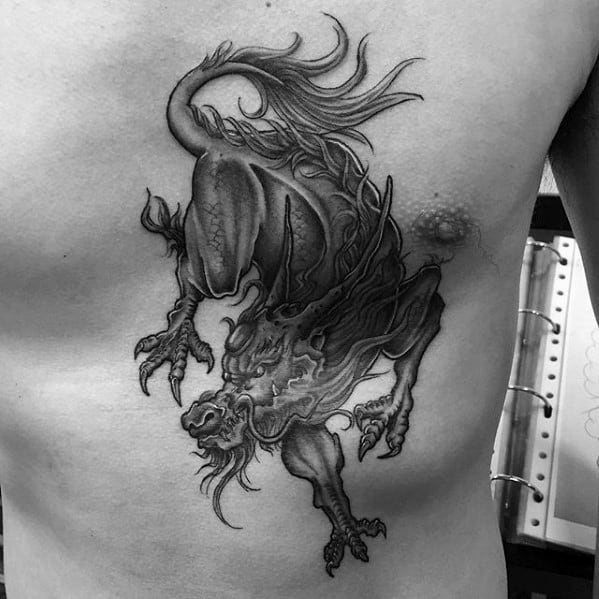 Detailed black and grey Kirin tattoo on the ribs, showing a dynamic pose with sharp claws, flowing mane, and intense facial expression.