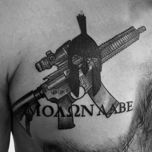 Black and grey chest tattoo featuring an AR-15, Spartan helmet, and "Molon Labe" text, symbolizing strength, defiance, and warrior spirit.