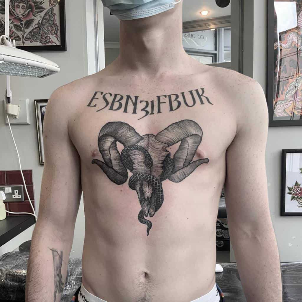 Chest tattoo featuring a detailed black ink ram skull with curved horns and a snake, along with bold lettering above