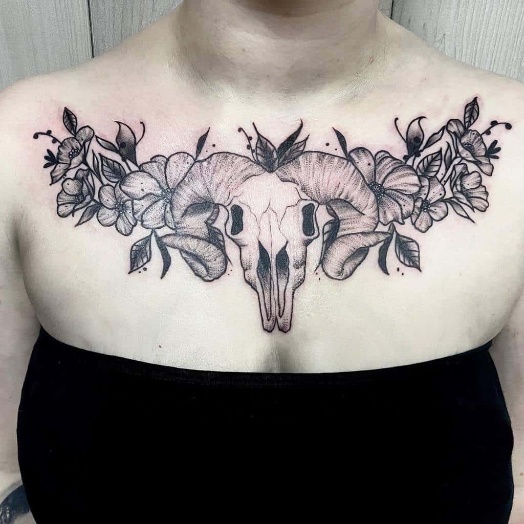 A chest tattoo of a ram skull, enveloped by large flowers and leaves