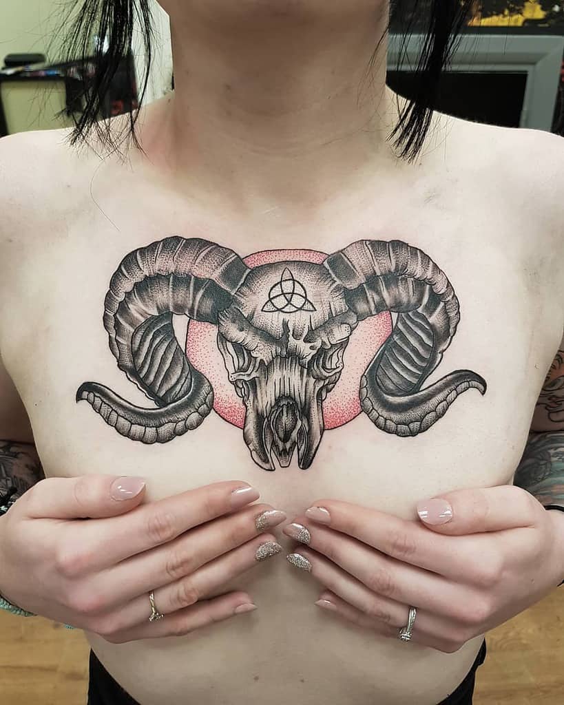 A woman holding their chest adorned with a vivid ram skull tattoo