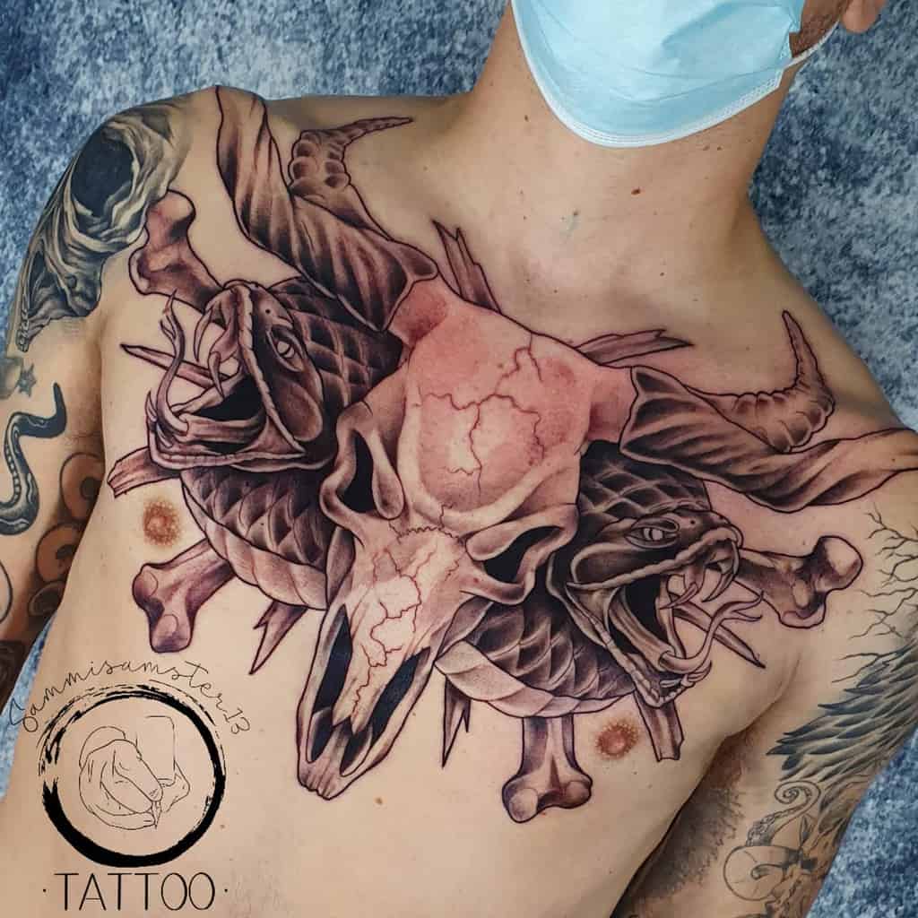 Chest tattoo of a cracked ram skull with two serpent-like creatures emerging from both sides