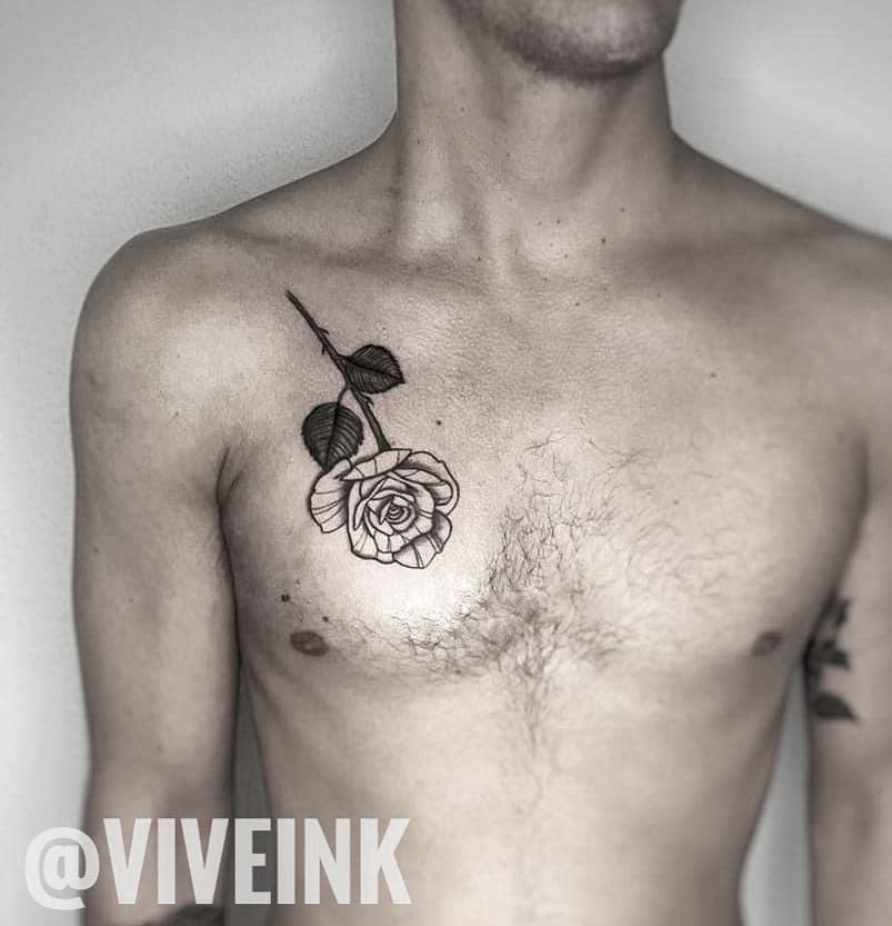 Minimalist black and gray rose tattoo with a stem and leaves, placed on the upper chest for a subtle yet elegant look
