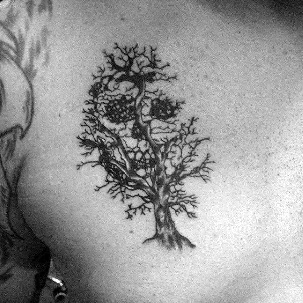 Chest tattoo of a leafless tree with twisted branches forming a subtle skull shape, combining nature and illusion art.
