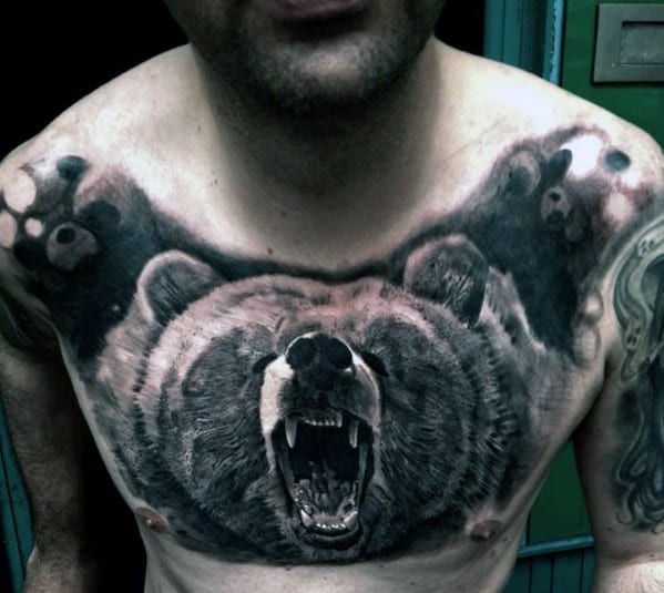 Man with detailed grizzly bear tattoo on his chest, featuring roaring bear and claws