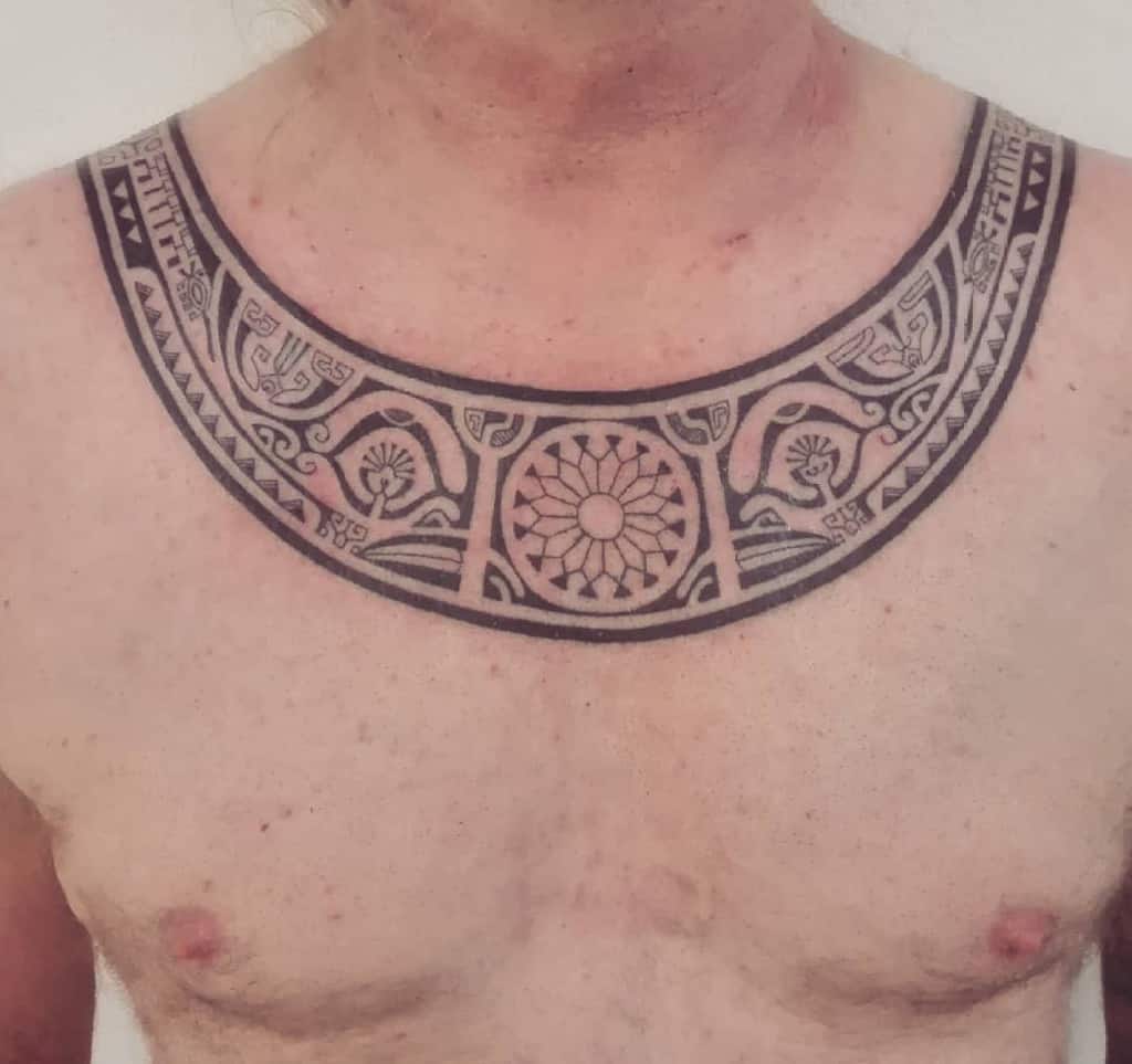 Bold tribal tattoo, featuring circular and geometric patterns with intricate detailing, forming a collar-like design