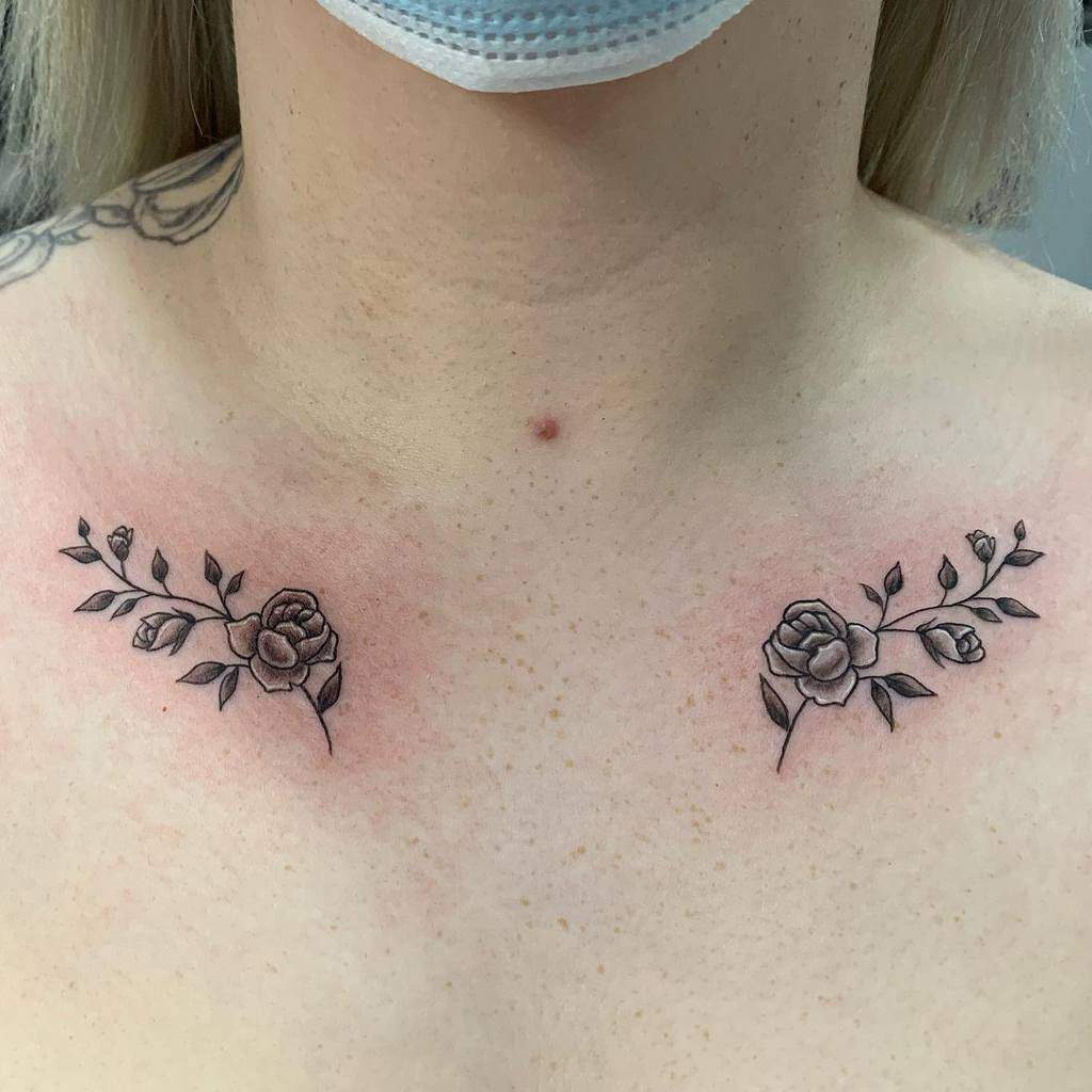 Close-up of two rose tattoos with leaves on a woman's upper chest