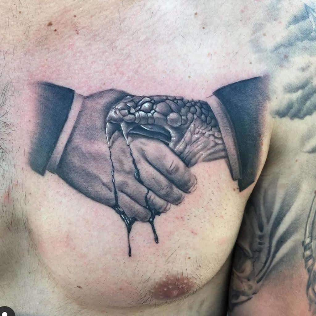Realistic black and gray chest tattoo of a handshake between a human hand and a snake, with detailed shading and dripping effect