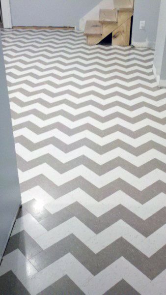 Chevron-patterned concrete floor, featuring alternating light and dark stripes, with stairs in the background