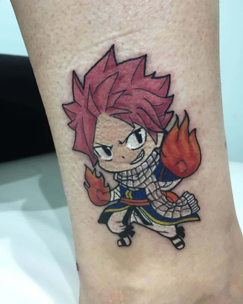 Chibi-style tattoo of Natsu Dragneel from Fairy Tail on the ankle, featuring bright colors, fiery fists, and a playful yet fierce expression.