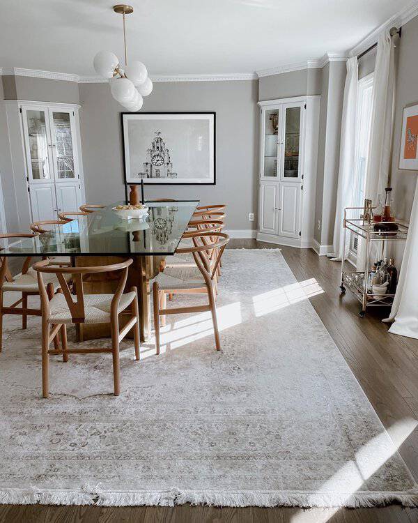 Chic boho dining room with a glass table, wishbone chairs, and soft neutral decor.