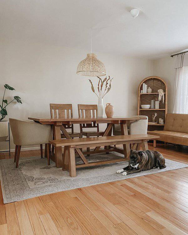 Chic boho dining room with natural wood furniture, woven lighting, and a cozy dog lounging.