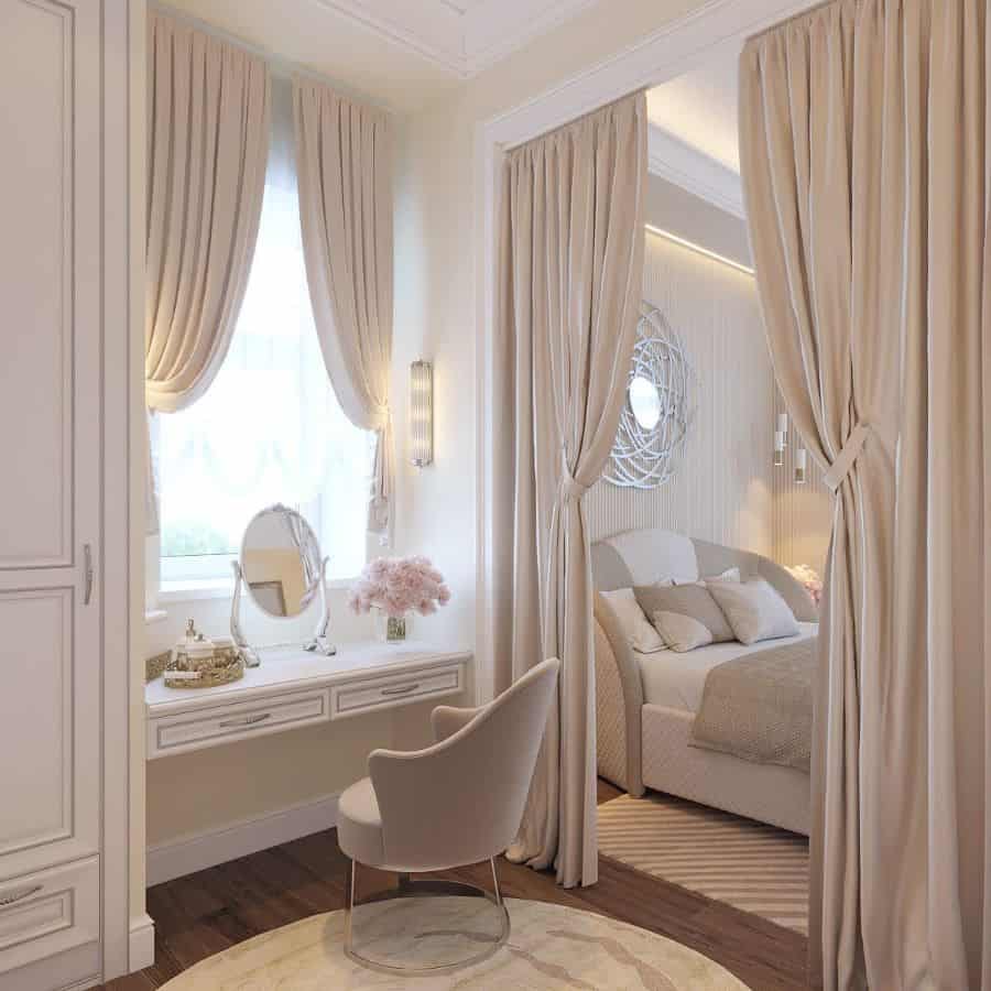 Elegant bedroom with cream curtains, vanity desk with chair, and soft lighting. Cozy bed seen through curtain divider
