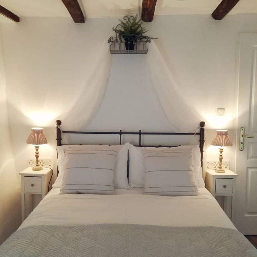 Cozy bedroom with a bed, two lamps on side tables, and a plant above the headboard in white and neutral colors