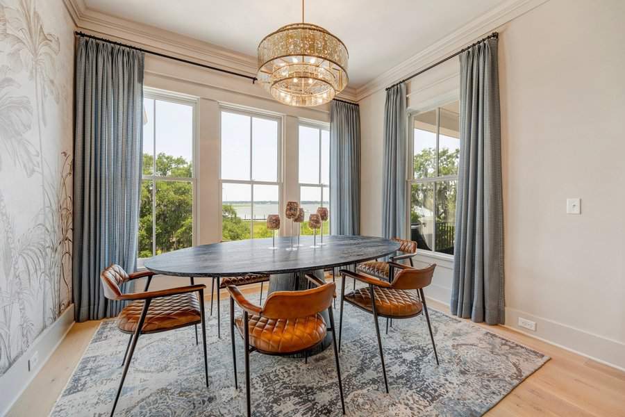 Elegant dining room with blue curtain panels, a statement chandelier, and leather accent chairs.
