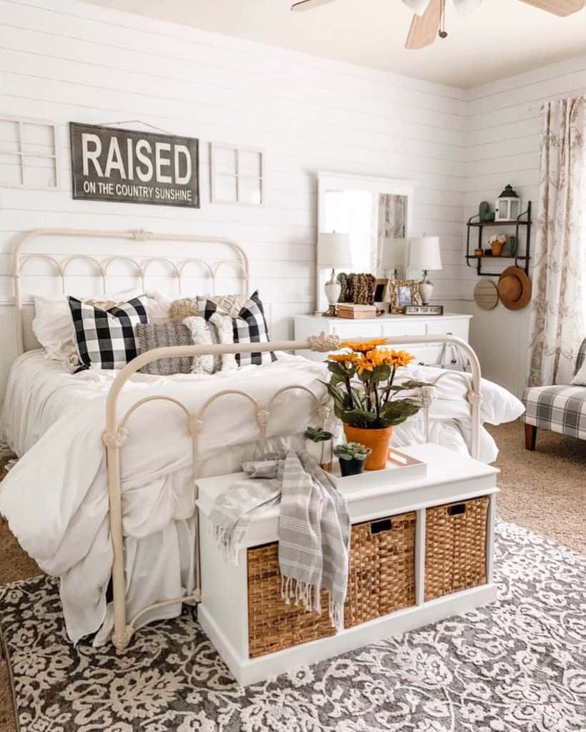 Farmhouse bedroom with a cozy metal bed, patterned pillows, floral decor, and rustic accents