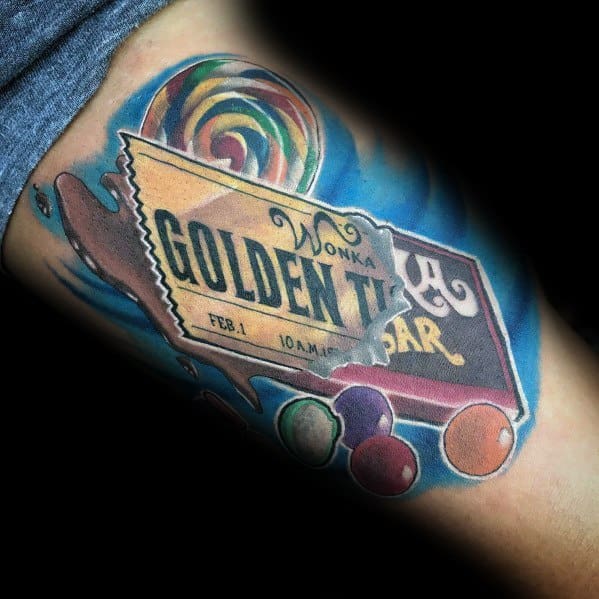 Colorful tattoo of a Wonka Golden Ticket and chocolate bar, surrounded by candies and a lollipop, with vibrant shading and a blue background.