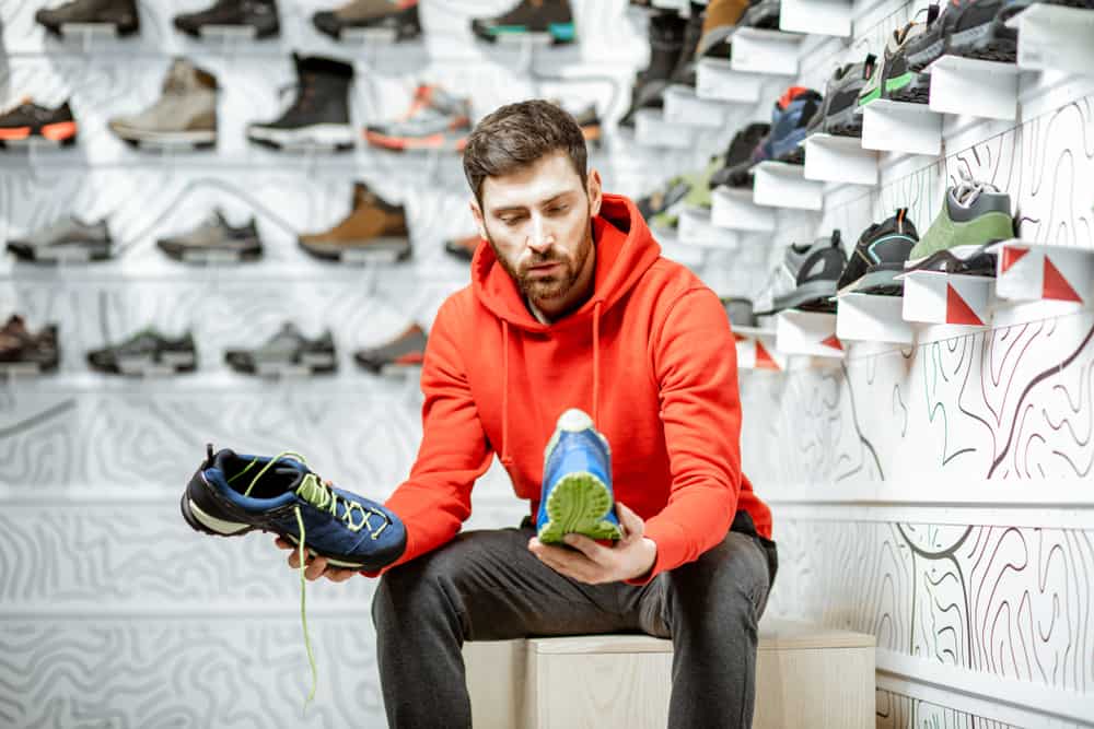 man choosing trail shoes in shop